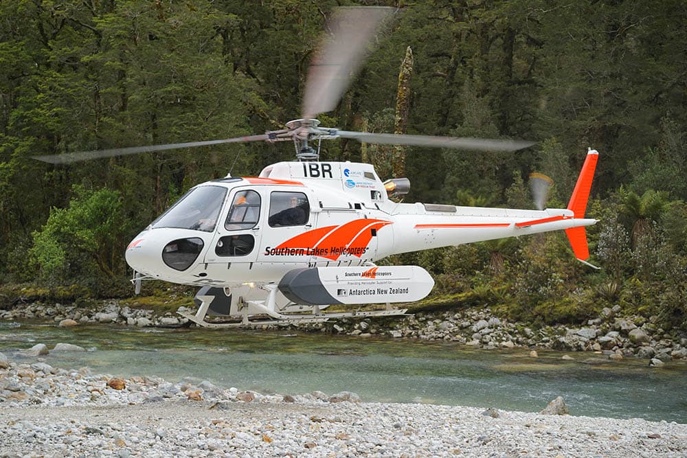 A helicopter landing on a riverbed to service trap lines