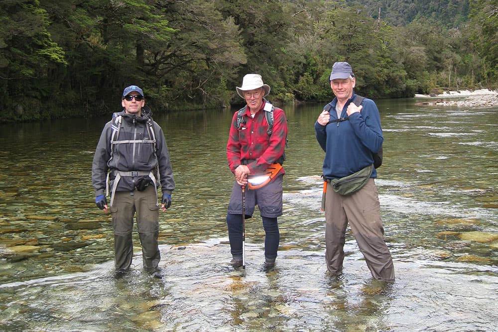 Three team members standing in a Fiordland river